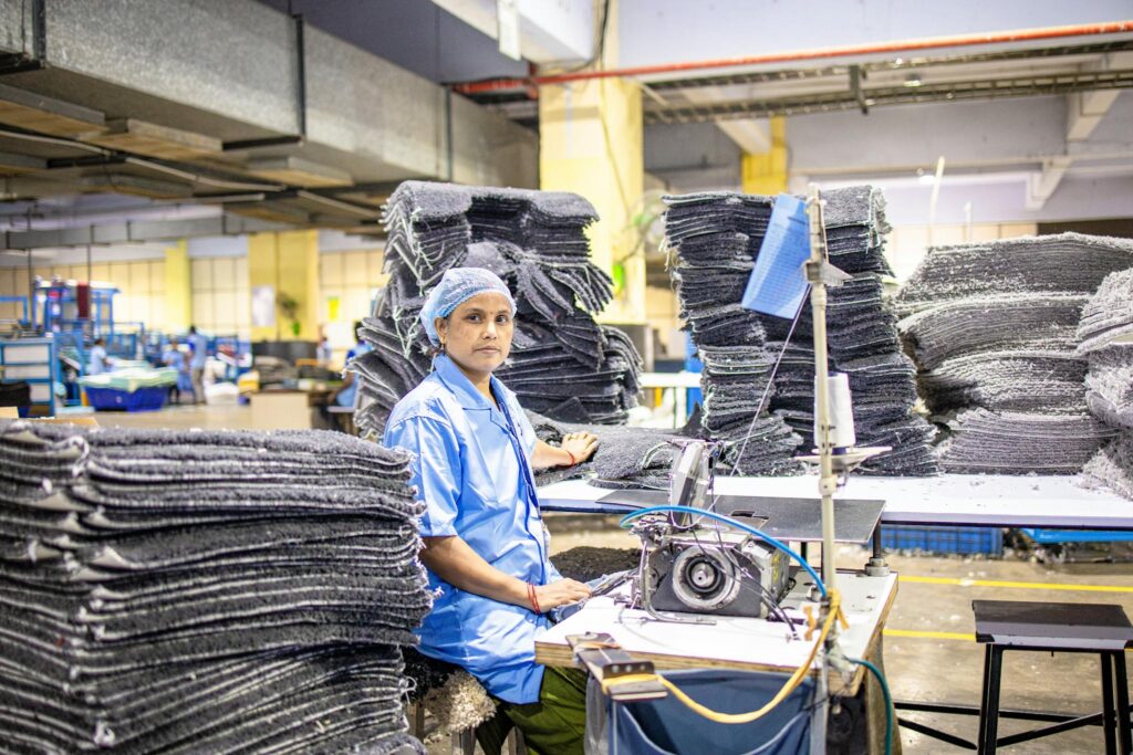 A dedicated worker operates machinery in a busy textile factory, showcasing a blue-collar work environment.