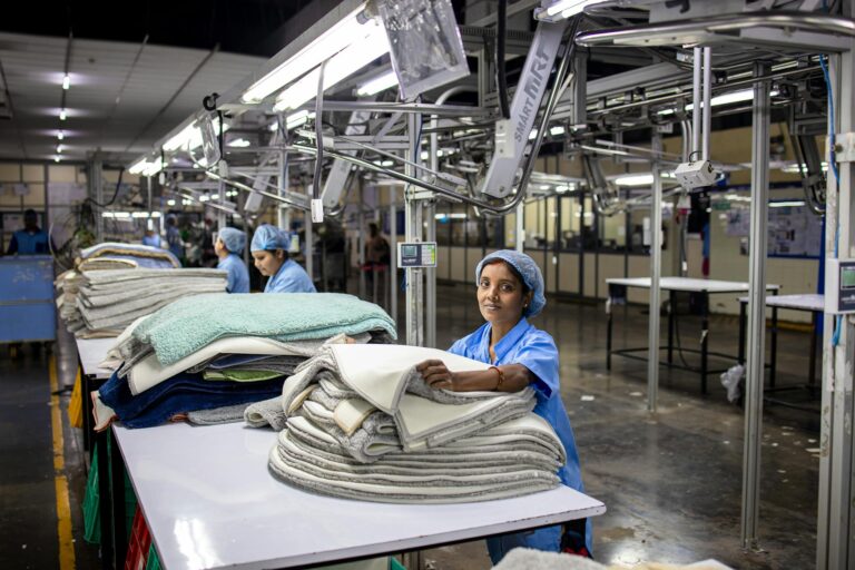 A female factory worker organizes textiles in an industrial setting, showcasing blue-collar work.